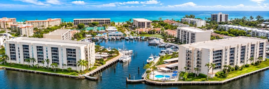 Aerial view of a luxury waterfront resort with a yacht marina, tropical landscaping, swimming pools, and the Atlantic Ocean.
