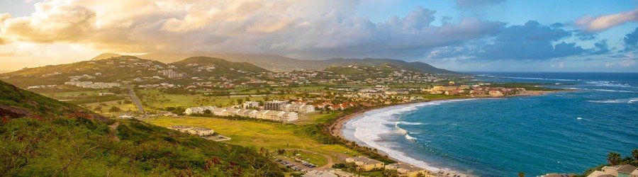 Panoramic coastal view of Basseterre, St. Kitts with mountains, beaches, and resorts.