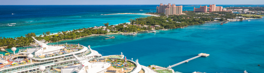 Aerial view of Nassau, Bahamas with cruise ships, turquoise water, and Paradise Island in the distance.