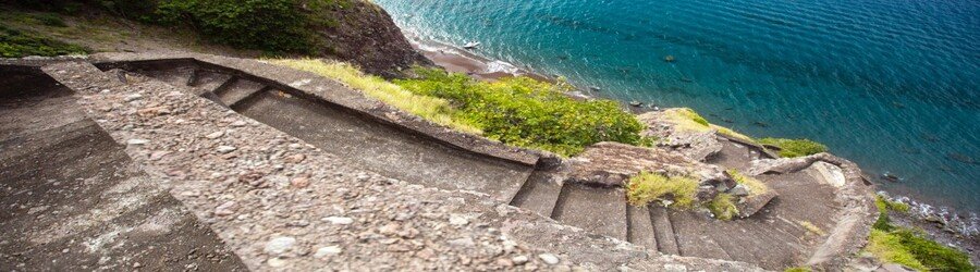 Steep stone steps descending toward the blue coastline at The Ladder on Saba