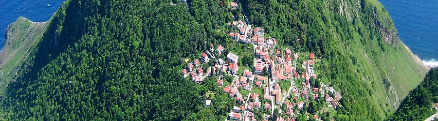 Aerial view of Saba’s hillside village with red-roofed houses surrounded by lush green mountains