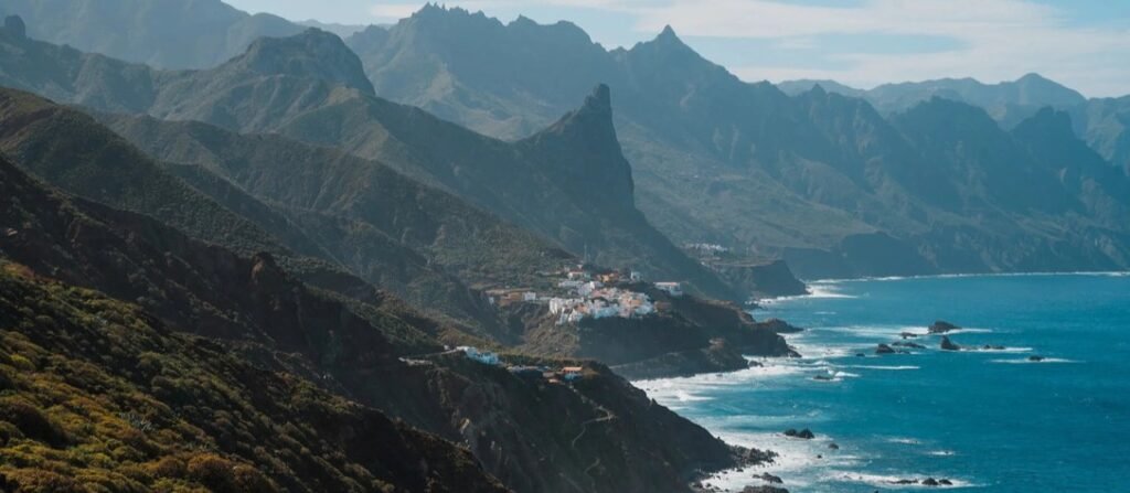 Dramatic jagged green volcanic mountains of Anaga Rural Park meeting the blue Atlantic Ocean coastline in Tenerife.