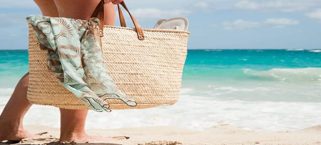 Enjoy the Best beach bags with this woven design and scarf detail on sandy shore by turquoise ocean waves.
