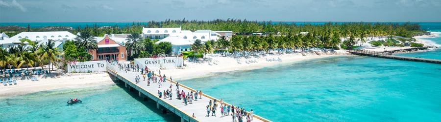 Grand Turk cruise port with visitors walking along the pier toward white-sand beaches and turquoise water in Turks and Caicos