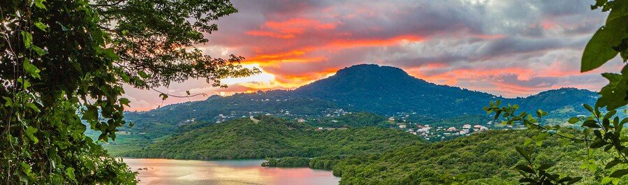 Tropical hills and coastal landscape in Martinique at sunset with lush greenery, water views, and dramatic sky
