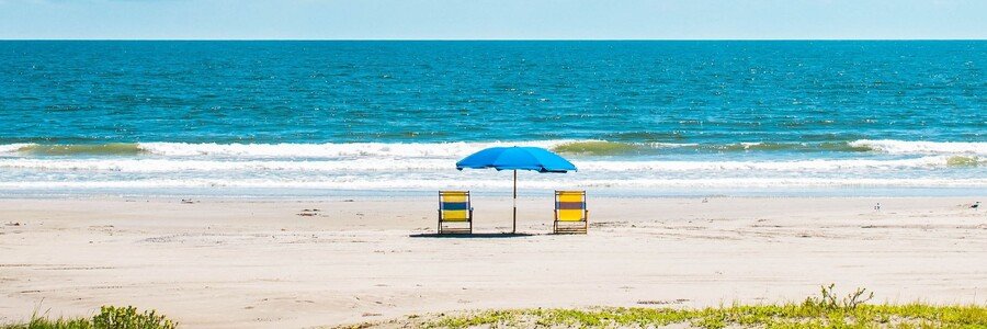 Rockport Beach Texas with sandy shoreline, calm Gulf water, beach chairs, and umbrella setup
