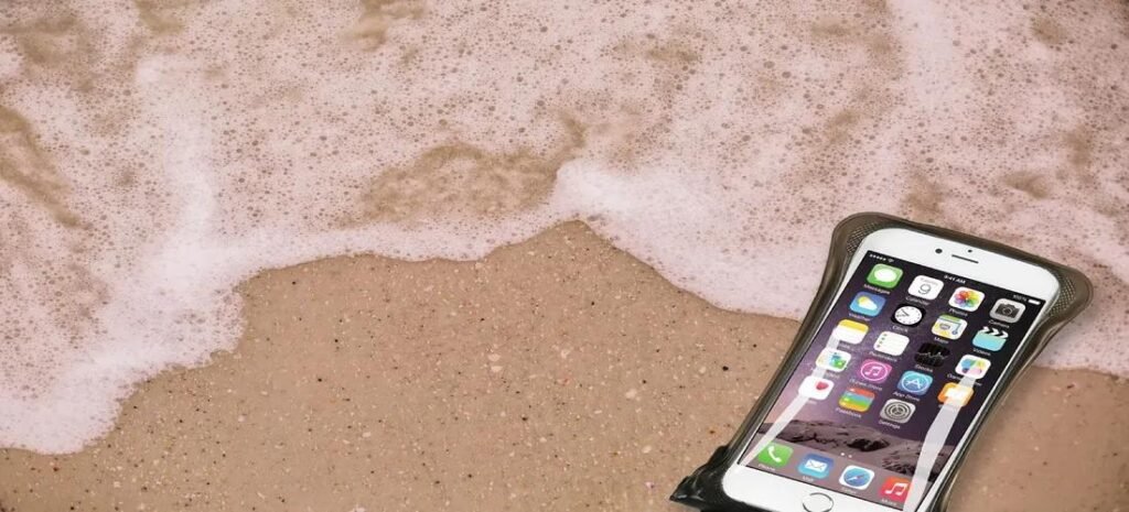 Smartphone in one of the best waterproof cases lying safely on the beach as waves wash over it.
