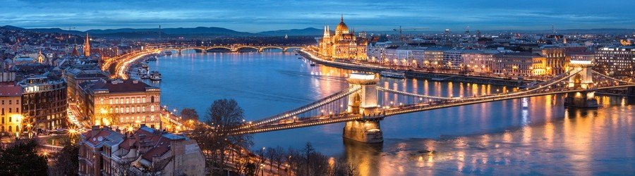 Night view of Budapest, Hungary, featuring the Hungarian Parliament Building and illuminated bridges crossing the Danube River.