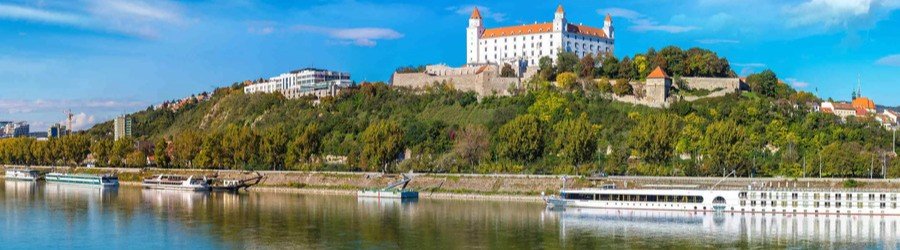 Bratislava Castle overlooking the Danube River and cruise ships docked below in Vienna, Austria.