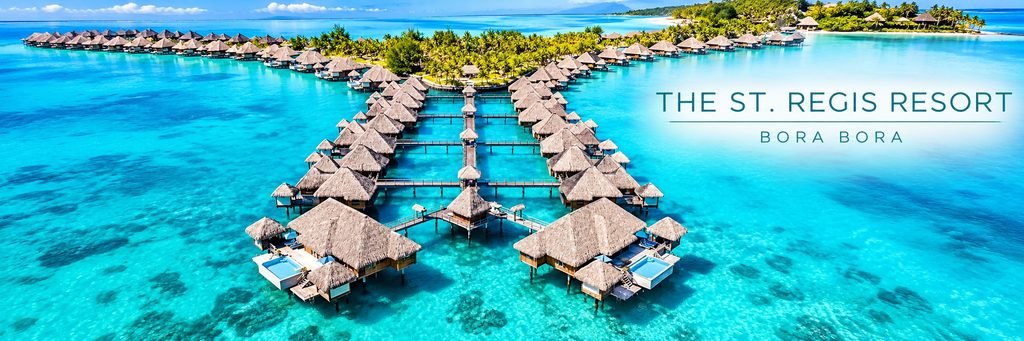 Aerial view of The St. Regis Resort featuring luxurious overwater villas, private pools, wooden walkways, and brilliant turquoise lagoon waters.