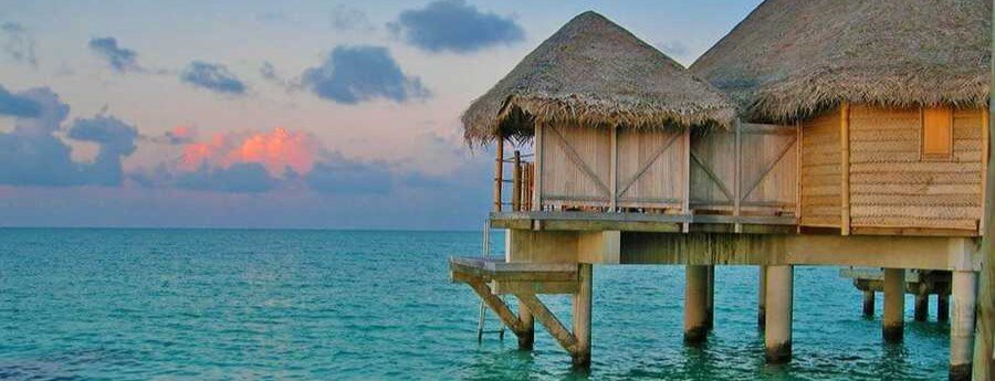 Overwater bungalows in Tahiti at sunset above turquoise lagoon