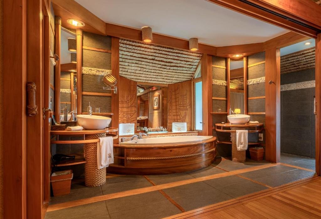 Luxury bungalow bathroom with soaking tub and wood interior at Le Taha’a by Pearl Resorts
