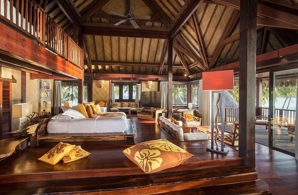 Spacious overwater bungalow interior with wood design at Vahine Private Island Resort