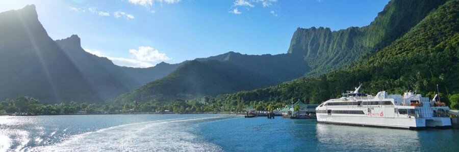 Ferry boat arriving at island port with mountains and lagoon in Tahaa French Polynesia