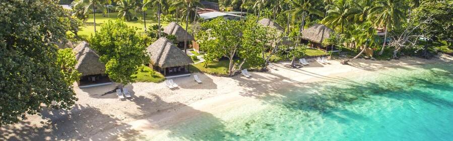 Beachfront bungalows and palm trees at Hotel Le Mahana in Huahine, French Polynesia