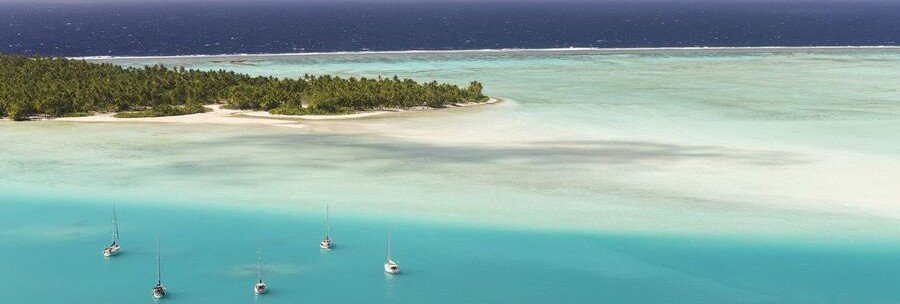 aerial view of Maupiti lagoon with motu islands and sailboats in French Polynesia