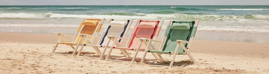 Colorful fabric beach chairs lined up on the sand with ocean waves in the background.