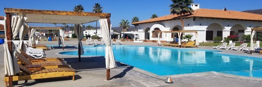 Ensenada beaches near Baja Sessions Resort and RV Park with a large outdoor pool, lounge chairs, shaded cabanas, and coastal-style buildings, creating a relaxed and open beachfront setting in Baja California Mexico