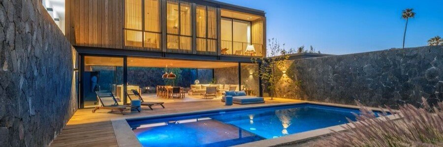 Ensenada beaches near Cuatro Cuatros luxury villa with a modern glass-front home, private pool, and stone walls at sunset, overlooking the coastal landscape of Baja California Mexico with a secluded and upscale atmosphere