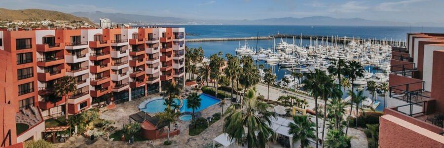 Ensenada beaches near Hotel Coral y Marina with oceanfront resort views, featuring a large marina filled with boats, palm-lined pool area, and coastal buildings overlooking the Pacific Ocean in Baja California Mexico