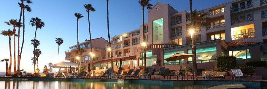 Ensenada beaches near Hotel Las Rosas Hotel and Spa at sunset with a glowing pool, palm trees, and coastal-style architecture illuminated at dusk, overlooking the Pacific Ocean in Baja California Mexico with a romantic and peaceful beachfront setting