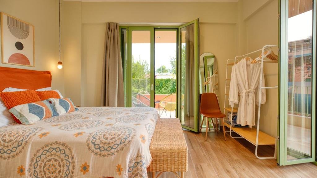 bright modern bedroom with patterned bedding, open balcony doors, and natural light at Alkyoni Luxury Apartments