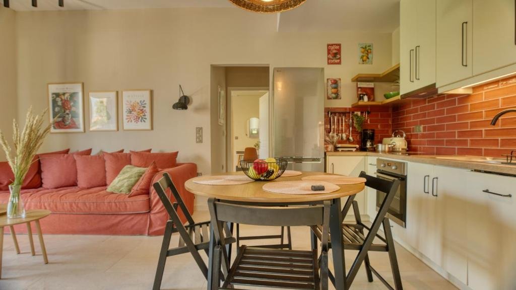 modern open plan living room and kitchen with dining table, sofa, and warm decor at Alkyoni Luxury Apartments