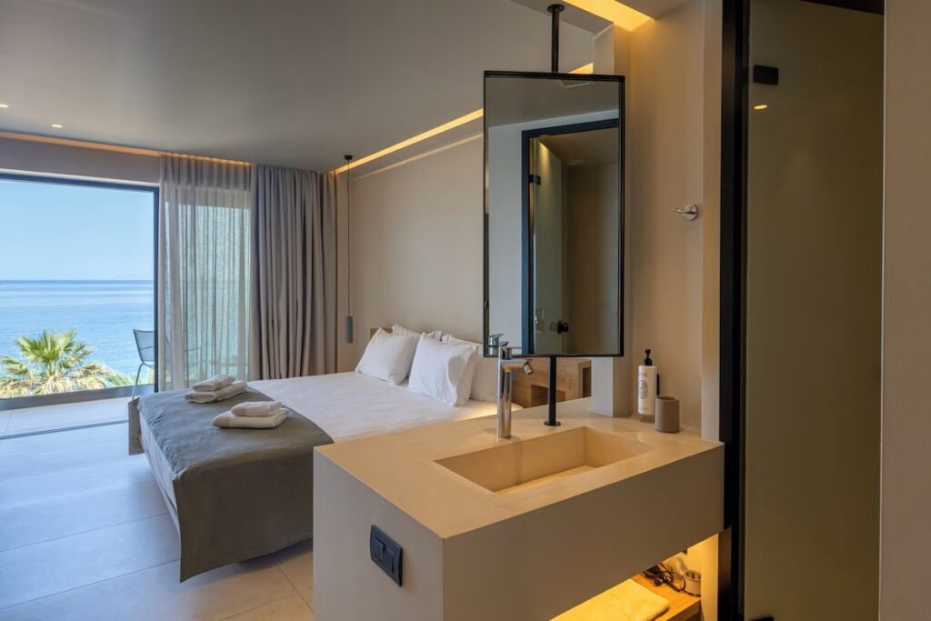 modern hotel room with ocean view, minimalist decor, and open bathroom at PHEIA Vriniotis Resorts