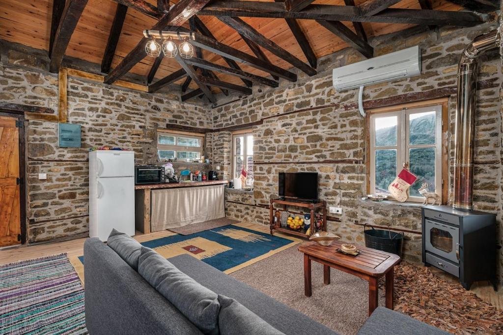 open rustic kitchen and living space with stone walls and wooden ceiling beams at Villa Riverwood