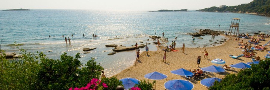 Agios Andreas Beach in Katakolon with golden sand, calm shallow water, and beach umbrellas along the Ionian coast