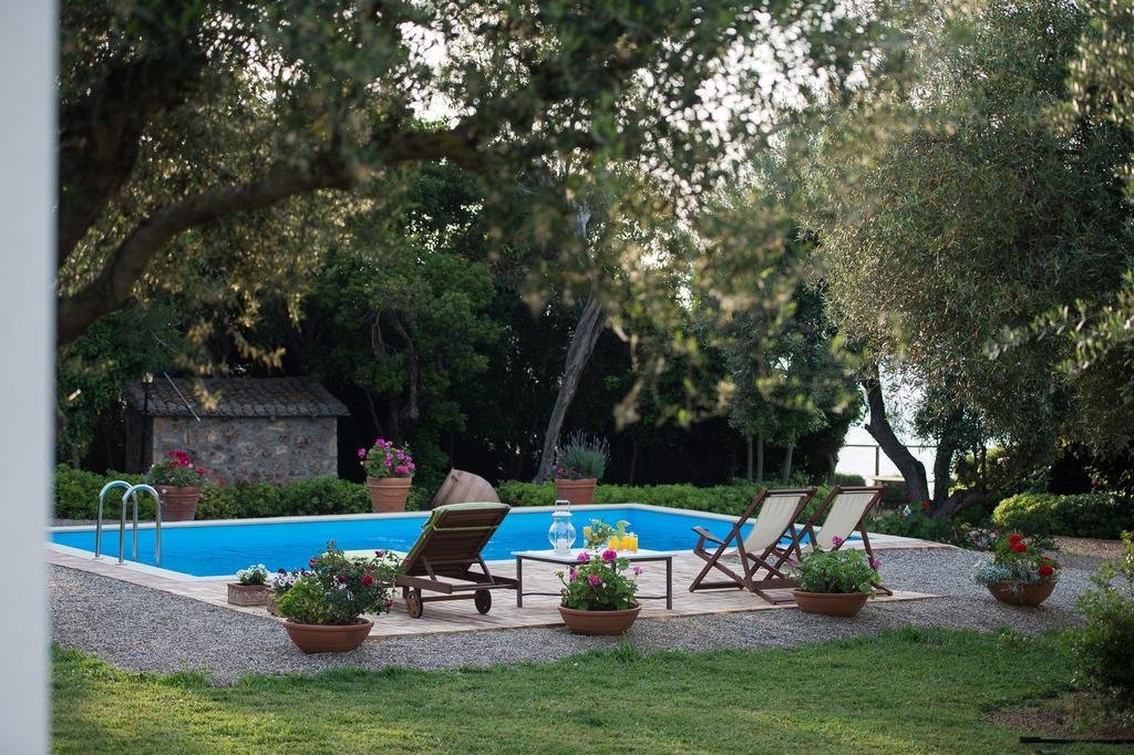 private pool with sun loungers surrounded by trees and flowers at Villa Feia Beach Hotel near Katakolon