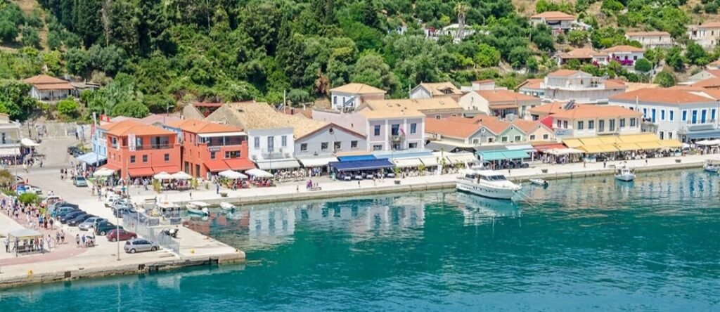 High-angle view of the colorful waterfront shops, cafes, and turquoise harbor in Katakolon, Greece.