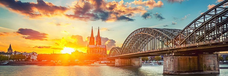 Cologne Cathedral and Hohenzollern Bridge at sunset along the Rhine River during a scenic European river cruise