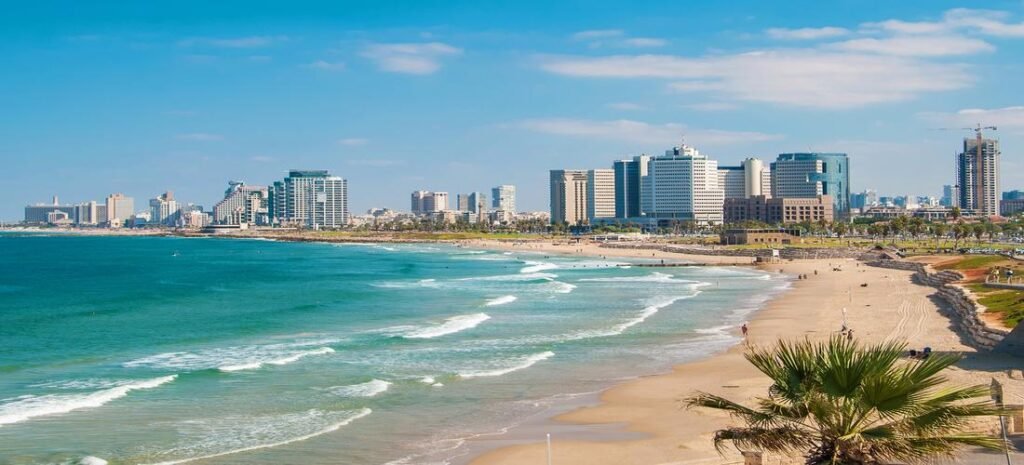 Skyline of Haifa with modern buildings along the Mediterranean coast and golden sandy beach.