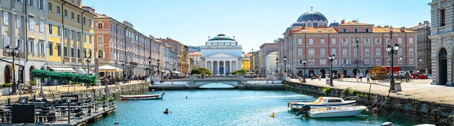 Canal Grande in Trieste Italy with pastel buildings, boats, and Sant’Antonio Nuovo Church in the background