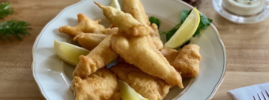 Plate of crispy Swiss Fischknusperli fried fish served with lemon wedges