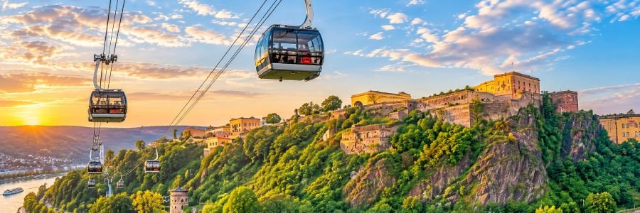 Koblenz cable cars traveling above the Rhine toward Ehrenbreitstein Fortress on a sunny hillside in Germany.