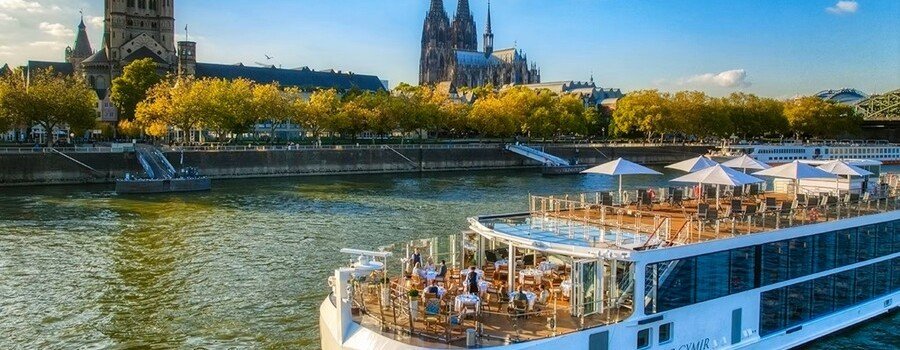 River cruise ship on the Rhine River with Cologne Cathedral and city skyline in the background