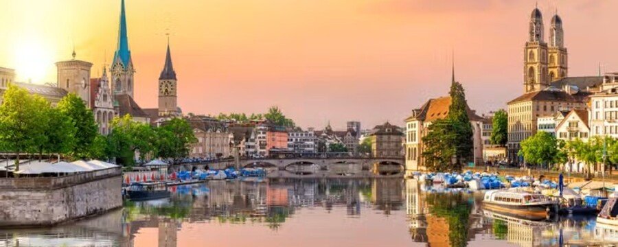 Zurich Old Town skyline at sunset with churches and reflections on the Limmat River