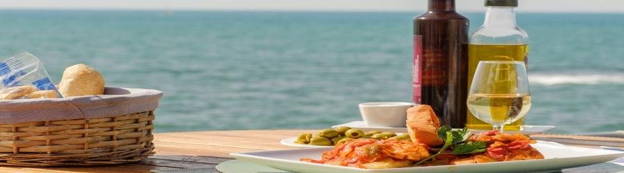 Traditional Italian seafood dish with bread, olives, wine, and olive oil served at a seaside restaurant in Barletta, Italy.