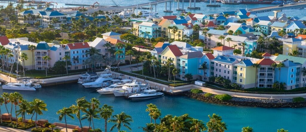 Colorful pastel buildings and boats along a turquoise marina in Nassau, Bahamas.