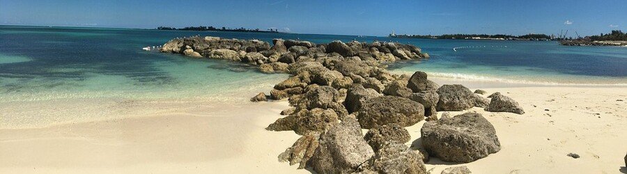 Calm turquoise water and rocky breakwater at Saunders Beach in Nassau.