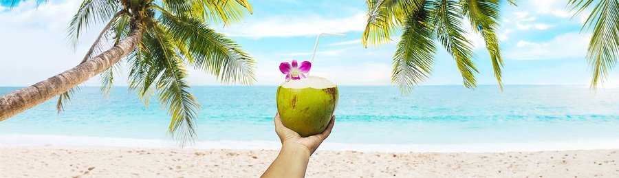 Caribbean tropical drink on Antigua and Barbuda beach with palm trees and ocean view