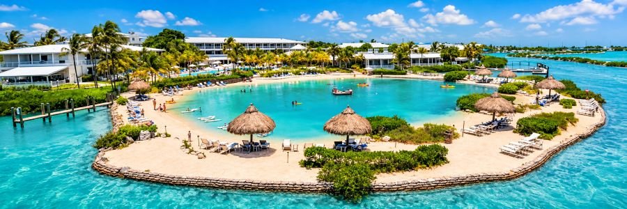Hawks Cay Resort in the Florida Keys featuring a turquoise saltwater lagoon, sandy beach, palm trees and waterfront resort buildings.