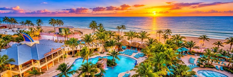 Margaritaville Hollywood Beach Resort in Florida featuring tropical pools, palm trees and beachfront views at sunset.