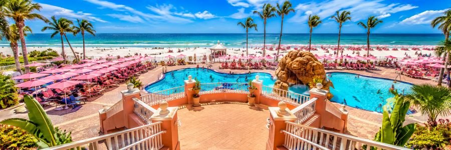 Pink Shell Beach Resort on Fort Myers Beach, Florida, featuring a beachfront pool, pink umbrellas, palm trees and Gulf views.