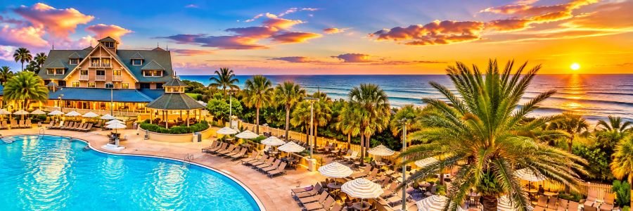 Disney’s Vero Beach Resort in Florida featuring a tropical swimming pool, palm trees and Atlantic Ocean views at sunset.