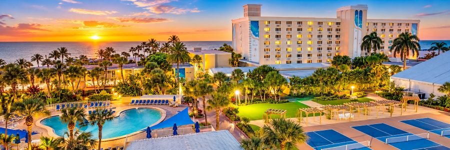 Island Grand at TradeWinds Resort on St. Pete Beach, Florida, featuring beachfront accommodations, a resort pool and tropical grounds at sunset.