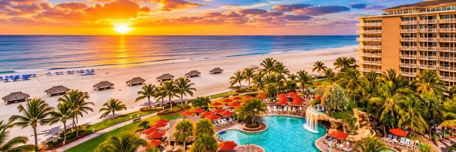 JW Marriott Marco Island Beach Resort in Florida featuring a tropical pool, palm trees, white-sand beach and Gulf views at sunset.
