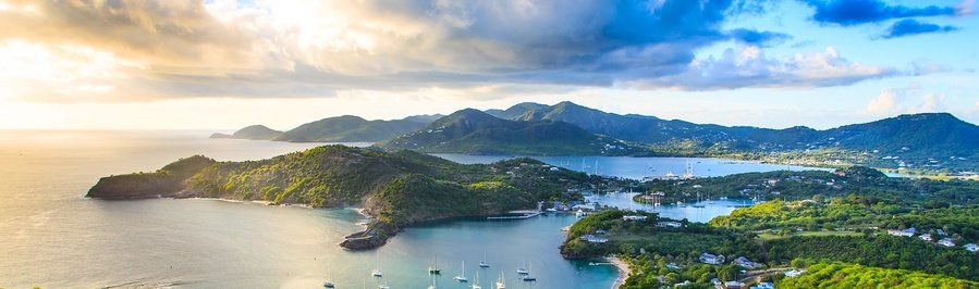 Antigua and Barbuda coastline with turquoise bays, sailboats, and lush Caribbean hills